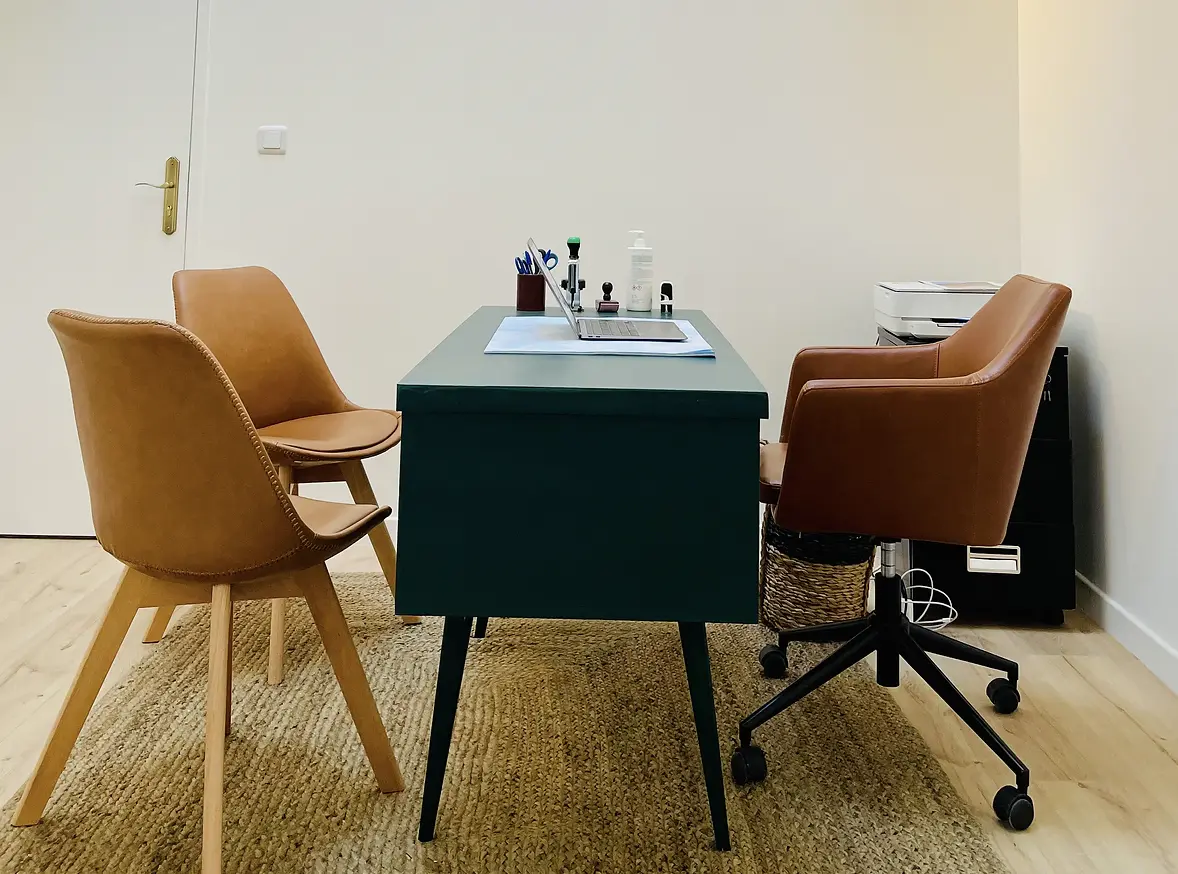 Le bureau de consultation : un bureau vert bouteille, deux chaises en cuir cognac, un tapis en jute
